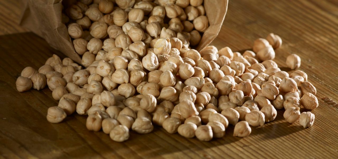 Chick-peas spilling on wooden surface --- Image by © SRS/Westend61/Corbis