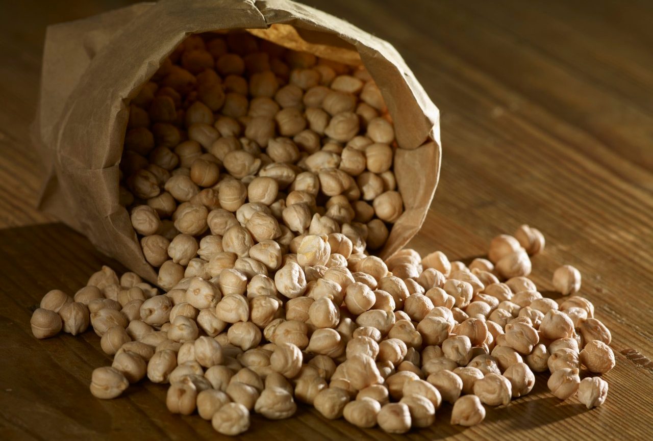 Chick-peas spilling on wooden surface --- Image by © SRS/Westend61/Corbis