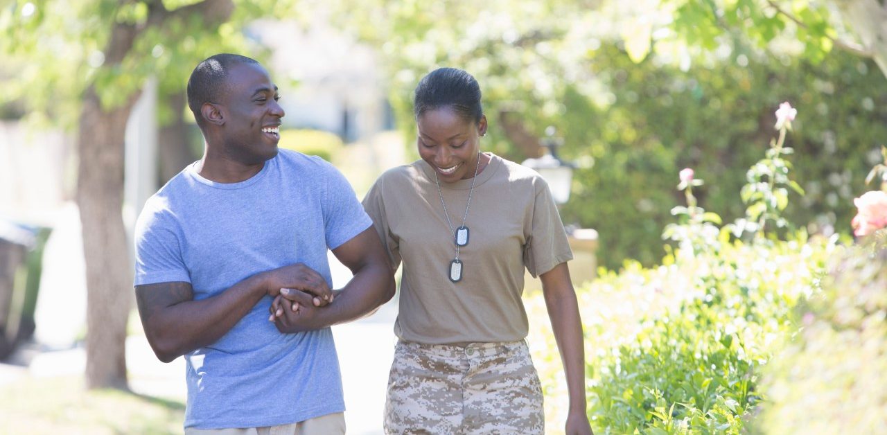 30 Mar 2014, USA --- Female soldier holding husband's hand whilst strolling on homecoming --- Image by © Raphye Alexius/Image Source/Corbis