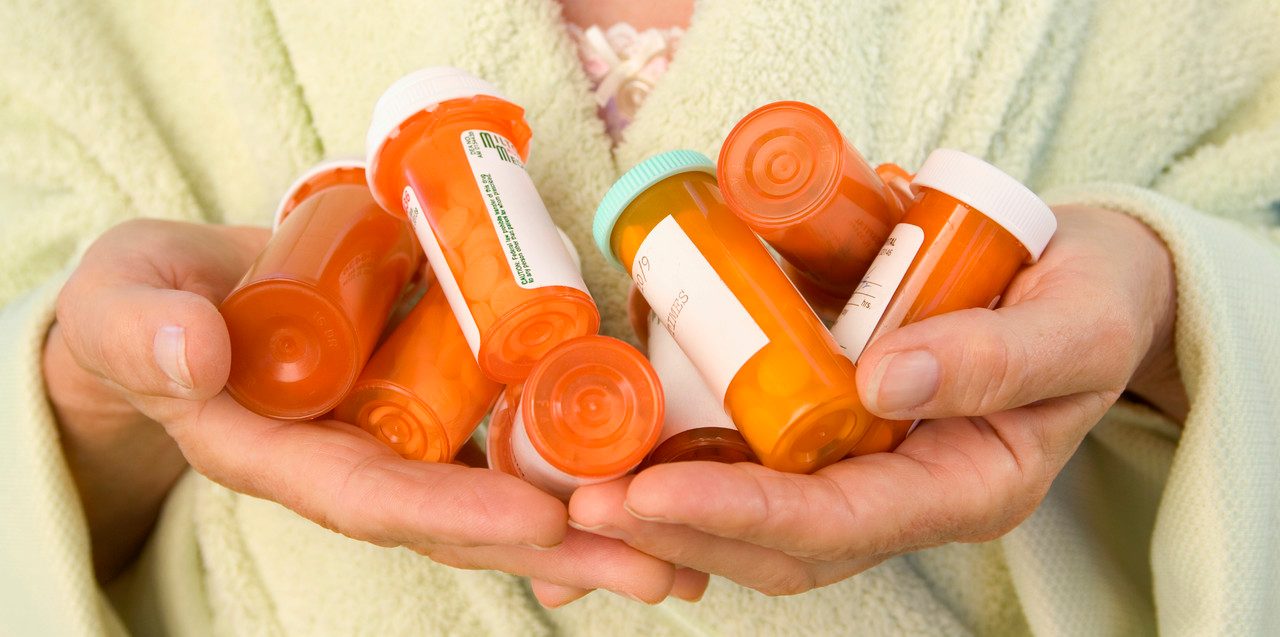 Senior Woman Holding Pill Bottles --- Image by © Paul Barton/Corbis