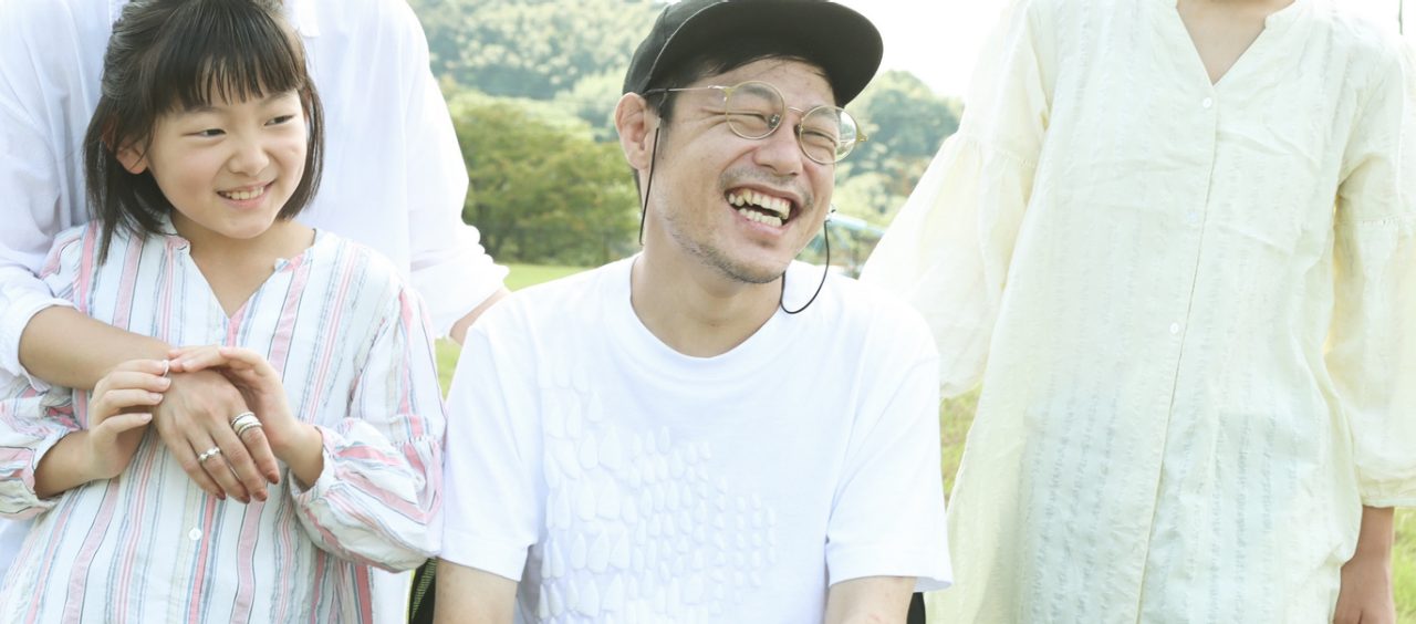 A portrait of a man living a positive and happy life with disabilities along with his supportive family.  Asian father has primary lateral sclerosis, a nerve disease gradually causing the body to stop moving.