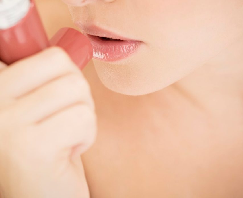 Female asthma sufferer using an inhaler --- Image by © I Love Images/Corbis