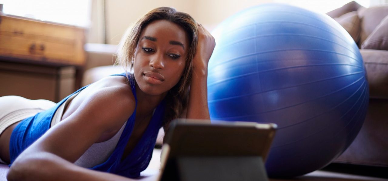 27 Jun 2014 --- Young woman taking a training break, using digital tablet in sitting room --- Image by © Kevin Kozicki/Image Source/Corbis