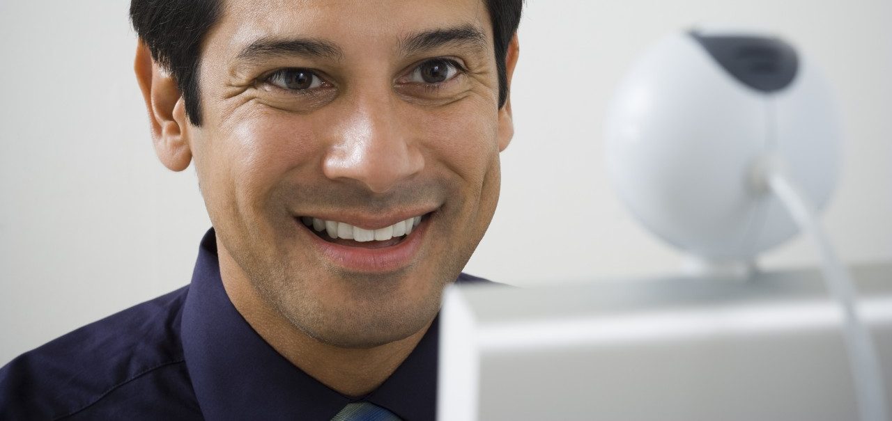 Close-up of a mature man smiling in front of a video conference camera --- Image by © Rubberball/Corbis