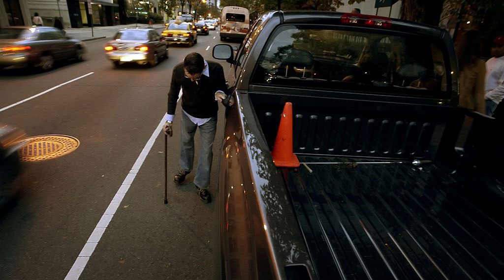 Man with a cane holding the door handle of his pickup truck