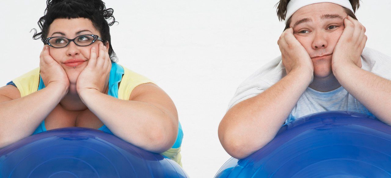 Disinterested overweight man and woman lying on Exercise Balls close up --- Image by © Mike Watson/moodboard/Corbis