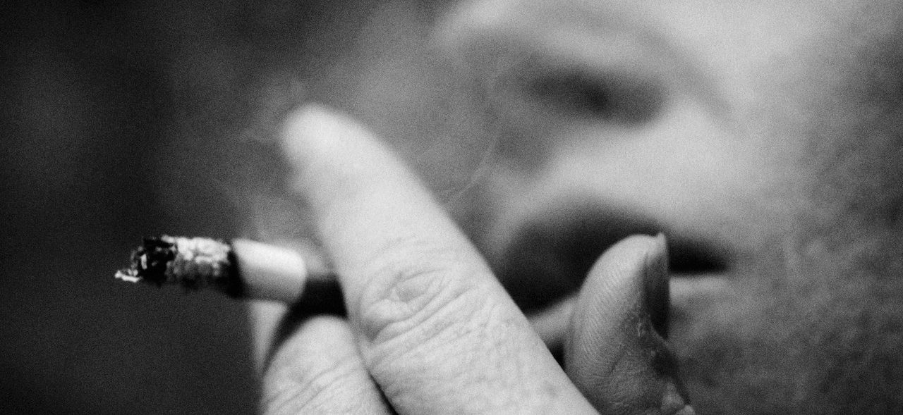 Person Smoking Cigarette, Close-up, Blurred, B&w --- Image by © Laurent Hamels/PhotoAlto/Corbis