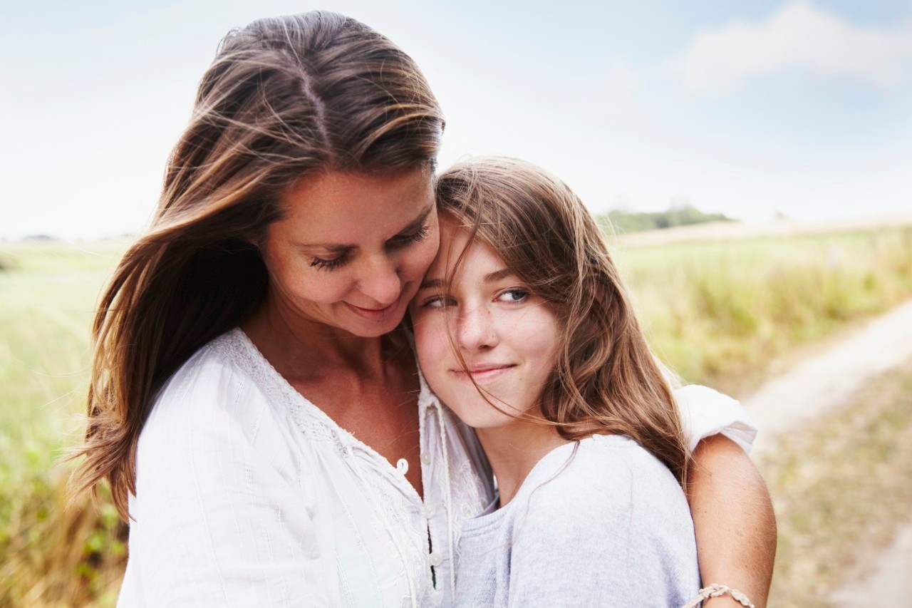 Portrait of mother embracing her daughter (13-15) outdoors --- Image by © Silke Woweries/Corbis