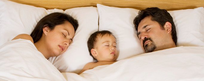 0042-11-30T06:00:00.000Z Parents Lying with Infant in Bed --- Image by © MM Productions/Corbis