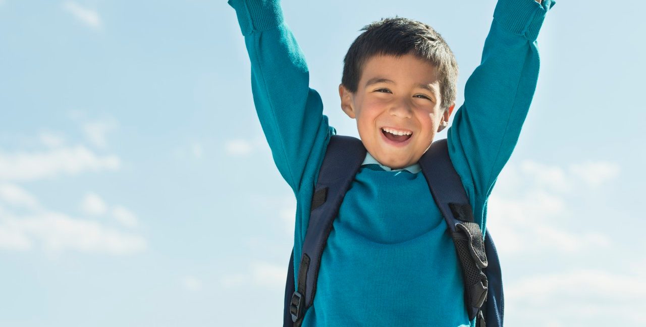 Boy (6-7) wearing backpack punching air --- Image by © Tetra Images/Corbis