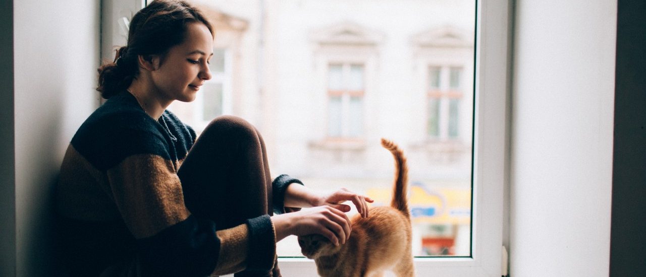 Girl sitting with cat on windowsill --- Image by © Oleh Slobodeniuk/Corbis