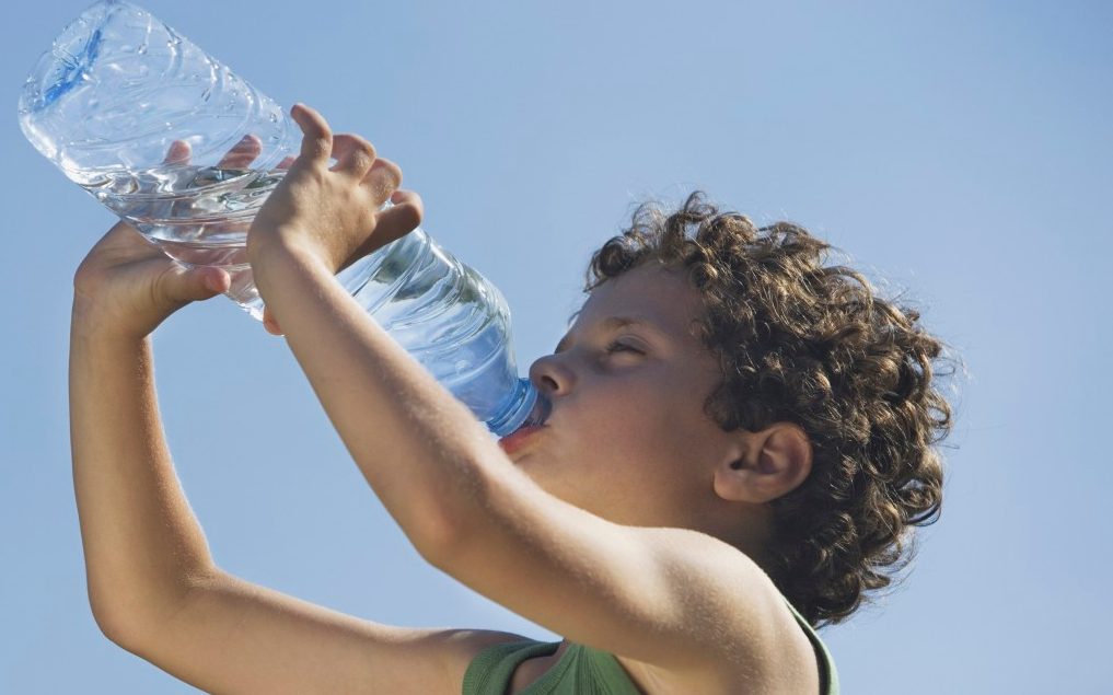 Low angle of young boy drinking water --- Image by © Steve Sparrow/cultura/Corbis