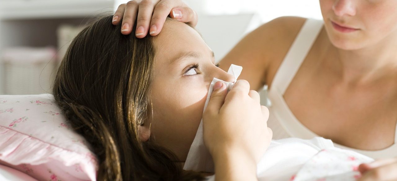 Girl with head cold, mother caressing forehead --- Image by © Laurence Mouton/PhotoAlto/Corbis