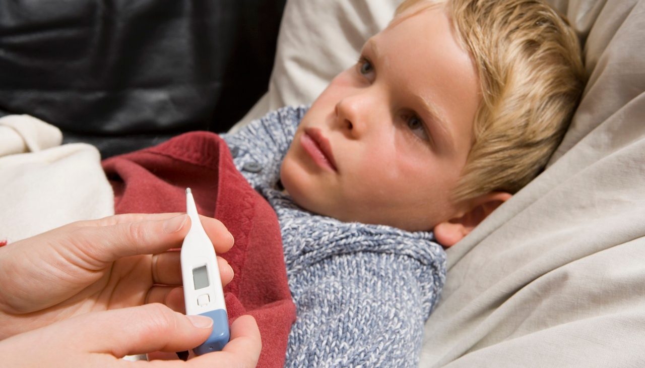 Sick child lying on back with digital thermometer --- Image by © Andreas Schlegel/fstop/Corbis