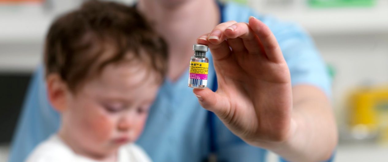 24 Aug 2010 --- MMR vaccine. Paediatrician with a phial of MMR vaccine and a 15 month old boy. --- Image by © TEK IMAGE/Science Photo Library/Corbis