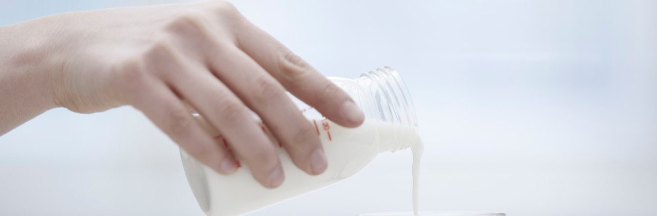 Hand pouring milk from bottle to glass --- Image by Â© Arman Zhenikeyev/Corbis