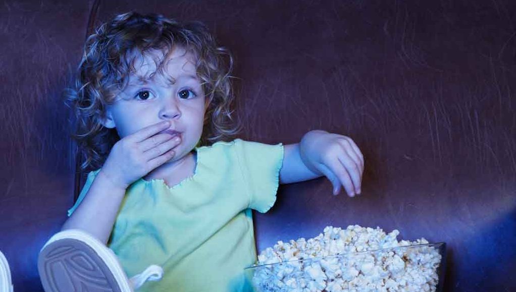 A toddler eating popcorn