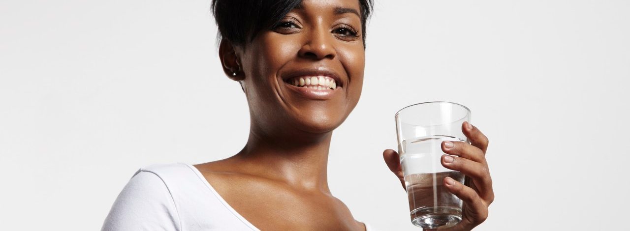 Studio portrait of woman holding glass of water --- Image by © pinkypills/Corbis