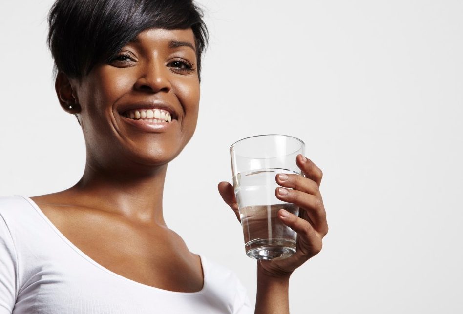Studio portrait of woman holding glass of water --- Image by © pinkypills/Corbis