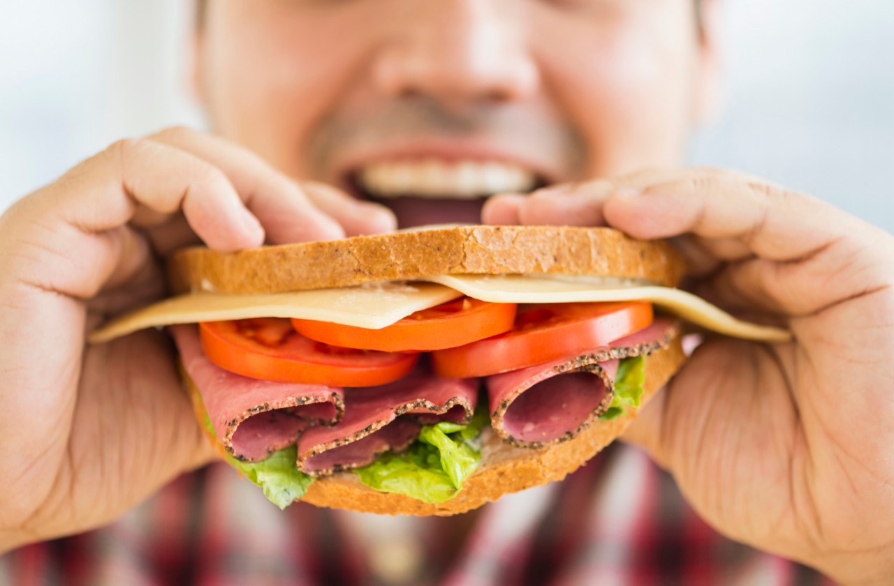 Mixed race man eating sandwich --- Image by © JGI/Tom Grill/Blend Images/Corbis