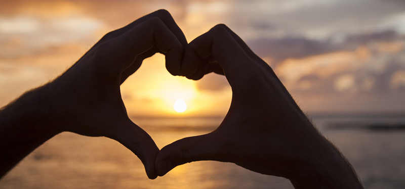 Close-up of man's hands making heart shape on beach. --- Image by © Leigh Righton/Corbis