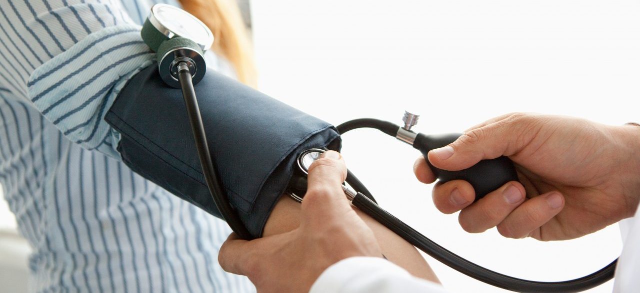 Doctor taking patient's blood pressure --- Image by © Hello Lovely/Corbis