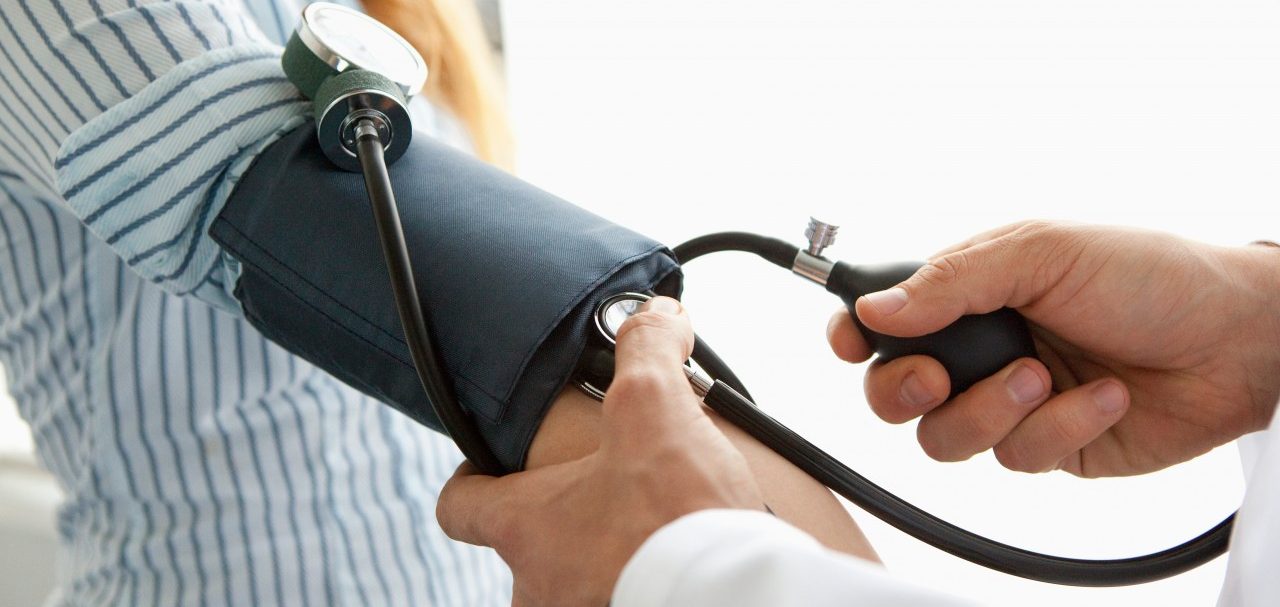Doctor taking patient's blood pressure --- Image by © Hello Lovely/Corbis