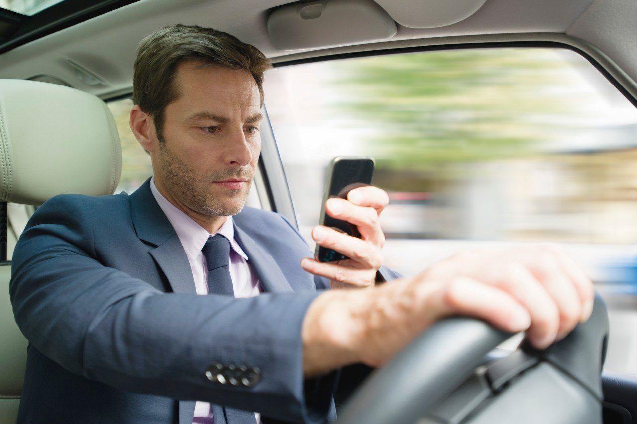 18 Jul 2013 --- Businessman looking at smartphone in car --- Image by © Frederic Cirou/PhotoAlto/Corbis