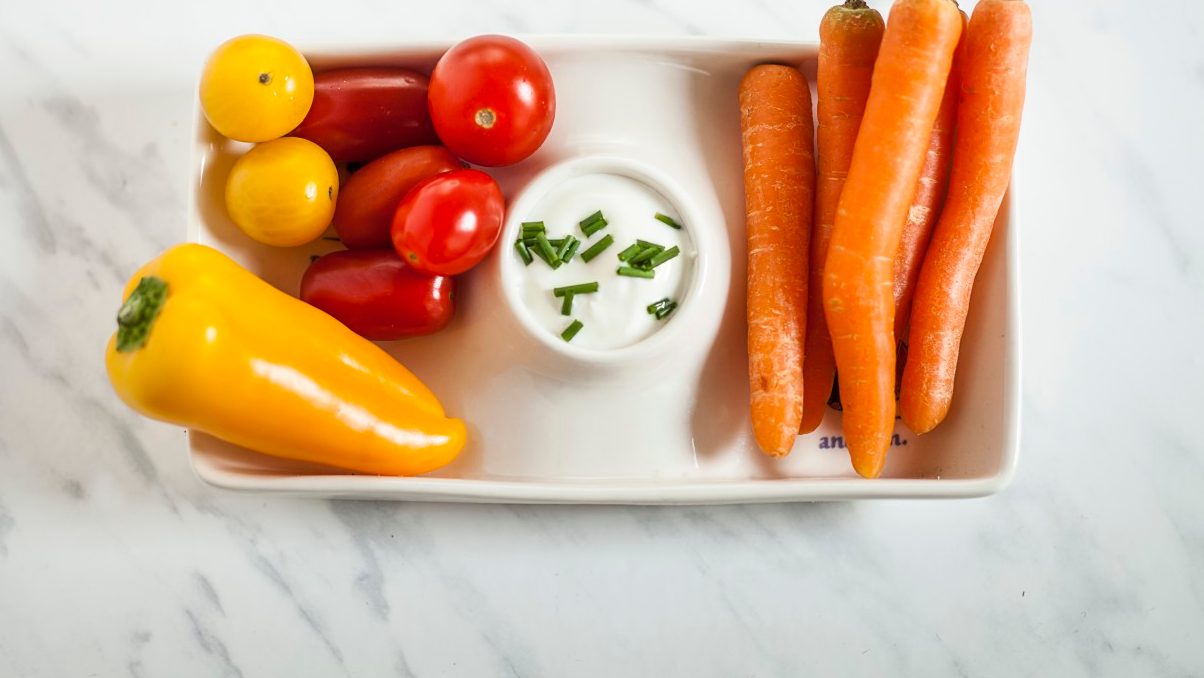 07 Nov 2014 --- Baby-sized vegetables, carrots, tomatoes, bell pepper with sour-cream-dip, toy car, studio --- Image by © Susan Brooks-Dammann/Westend61/Corbis