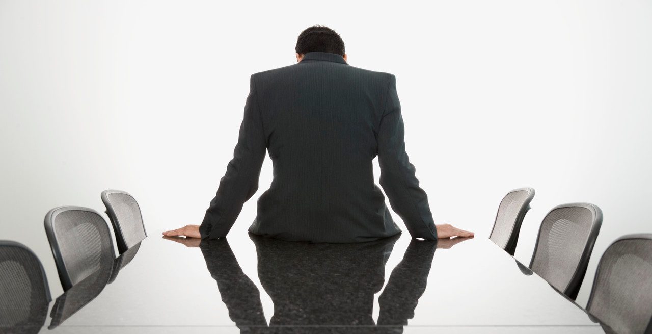 Businessman sitting slouched on edge of conference table --- Image by © Steve Hix/Somos Images/Corbis