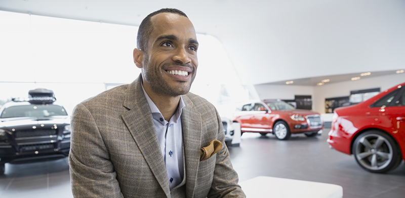 09 May 2014 --- Smiling man in car dealership showroom --- Image by © Hero Images Inc./Hero Images Inc./Corbis