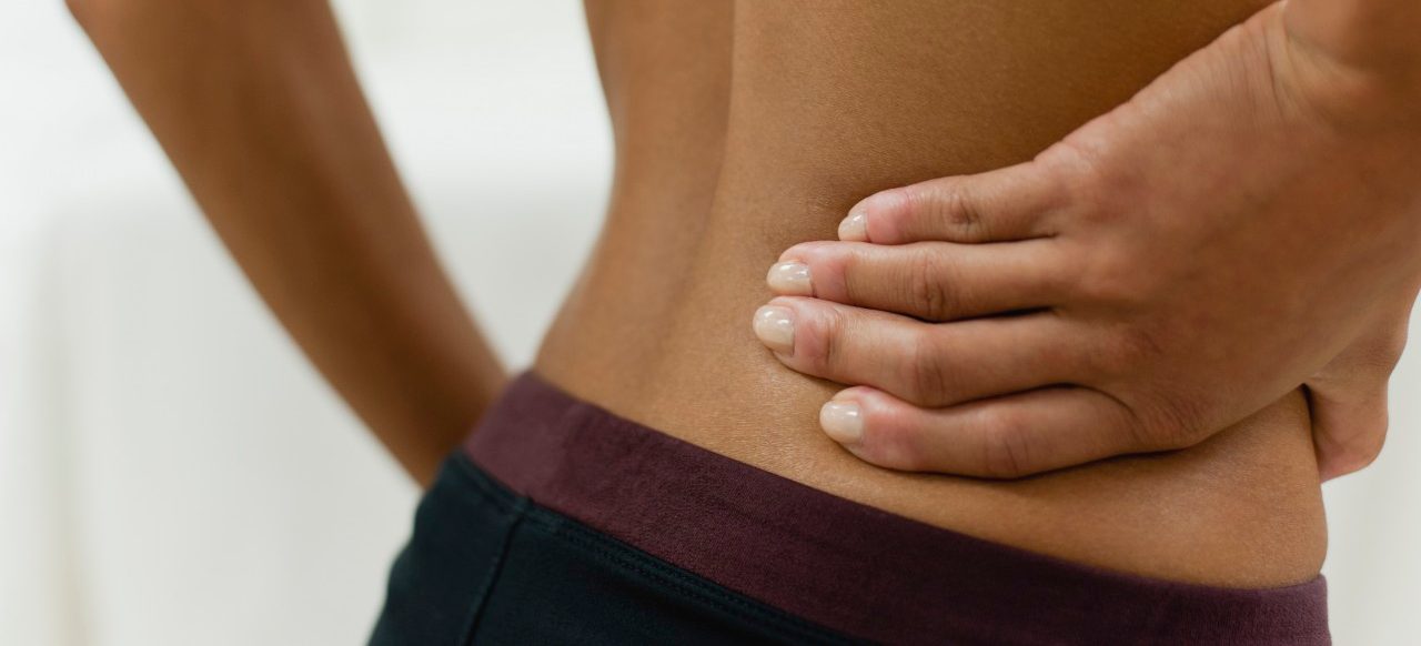 Woman with hand on lower back, mid section --- Image by © Odilon Dimier/PhotoAlto/Corbis