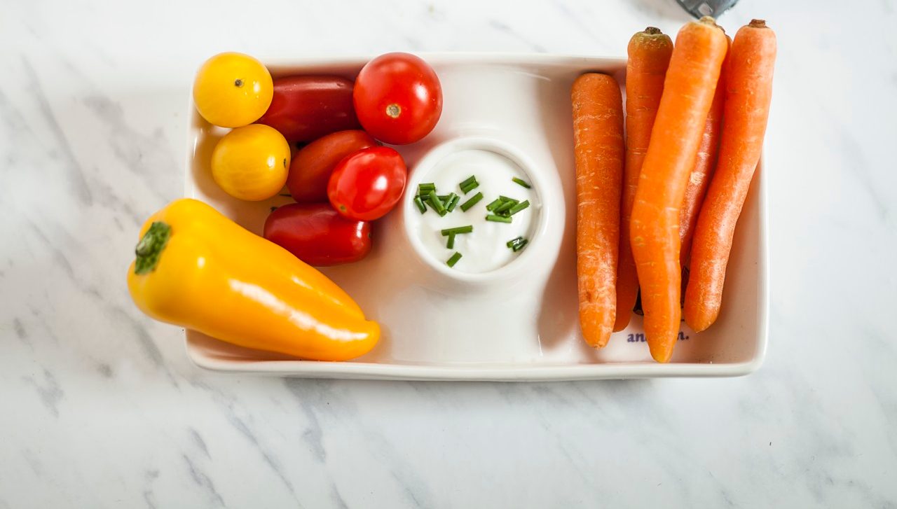 07 Nov 2014 --- Baby-sized vegetables, carrots, tomatoes, bell pepper with sour-cream-dip, toy car, studio --- Image by © Susan Brooks-Dammann/Westend61/Corbis