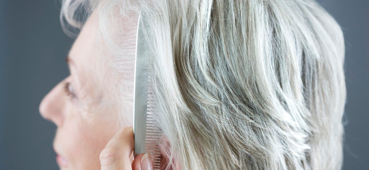 A senior woman combing her hair --- Image by © I Love Images/Corbis