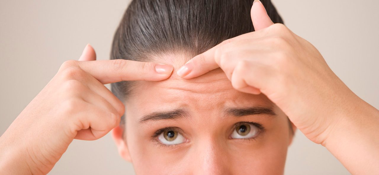 Close up of teenage girl popping pimple --- Image by © Jose Luis Pelaez, Inc./Blend Images/Corbis