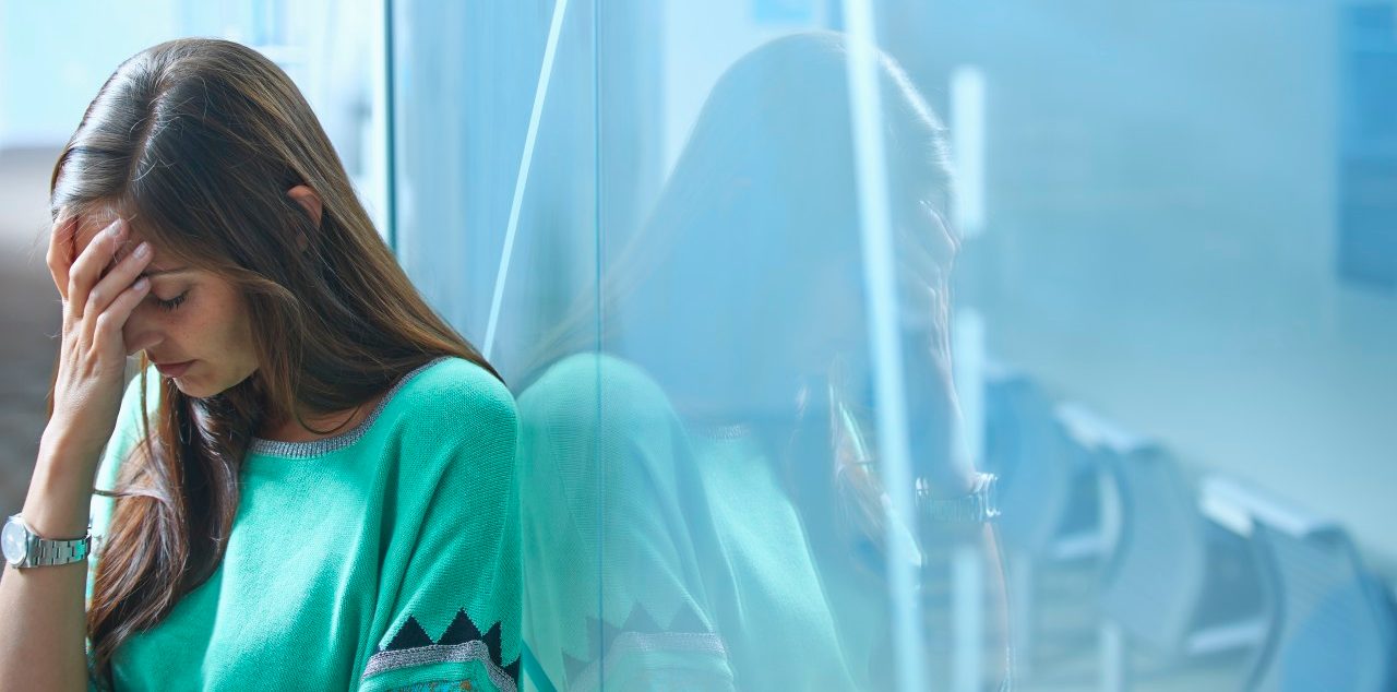 25 Apr 2014 --- Mid adult businesswoman leaning against glass wall in office with hand on face --- Image by © Ghislain & Marie David de Lossy/Corbis