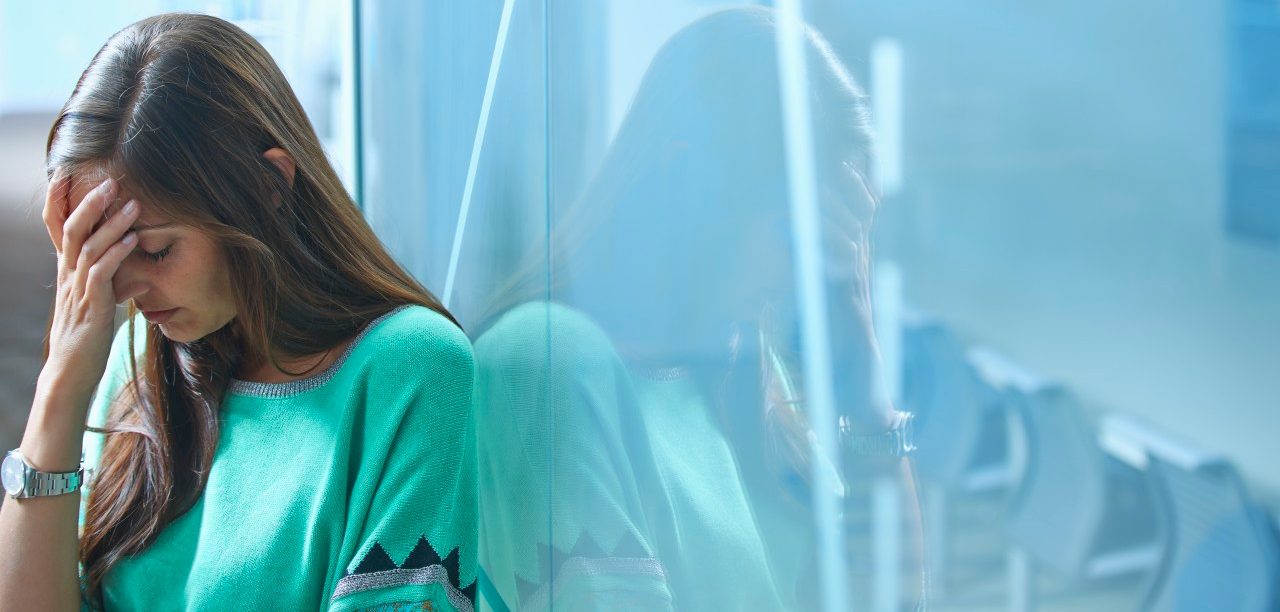 25 Apr 2014 --- Mid adult businesswoman leaning against glass wall in office with hand on face --- Image by © Ghislain & Marie David de Lossy/Corbis