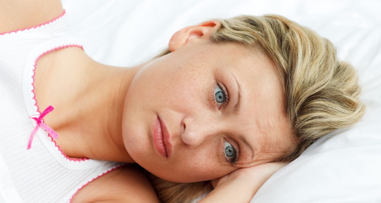 Portrait of upset woman lying in bed --- Image by © Wavebreak Media Ltd/Veer/Corbis