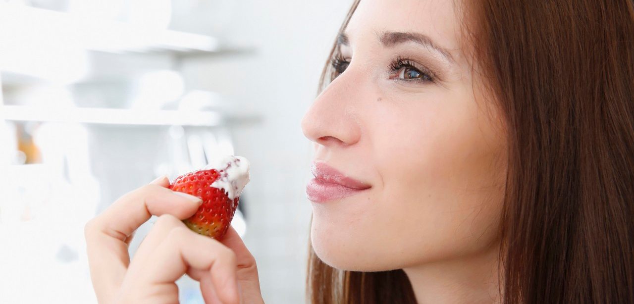 15 Feb 2014 --- Young woman enjoying a strawberry dipped in whipped cream --- Image by © Axl Images/Corbis
