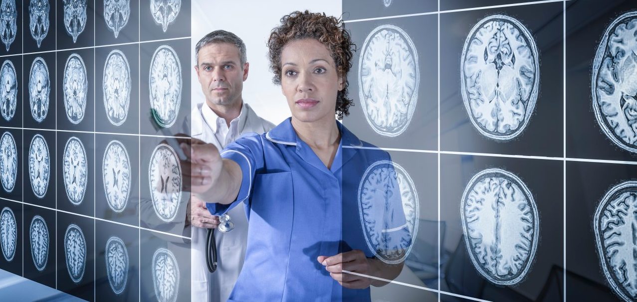 Doctor and nurse working with MRI brain scans seen through interactive display --- Image by © Monty Rakusen/Corbis