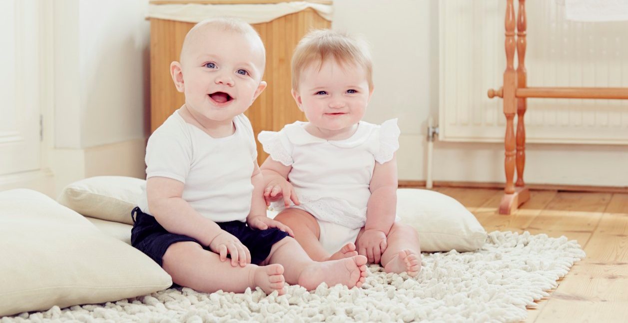 18 Jun 2014 --- Portrait of smiling baby girl and baby boy sitting on rug --- Image by © Emma Kim/Cultura/Corbis