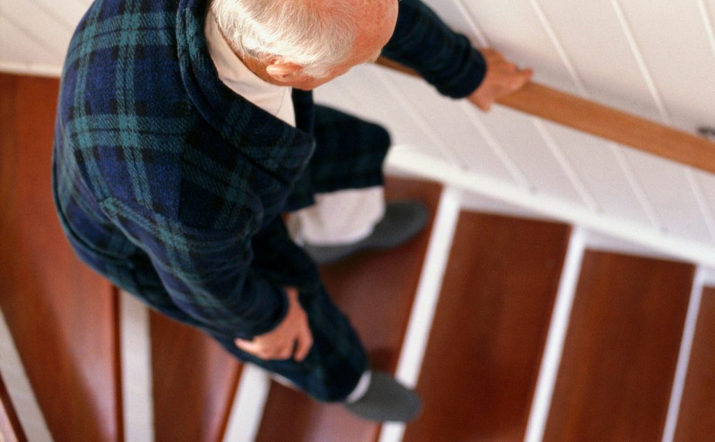 An elderly man carefully descends a staircase --- Image by © Whisson/Jordan/Corbis