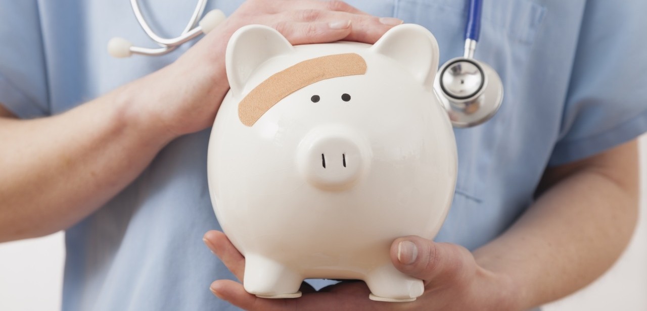 2011 --- Nurse holding piggy bank, midsection --- Image by © Greg Vote/Tetra Images/Corbis