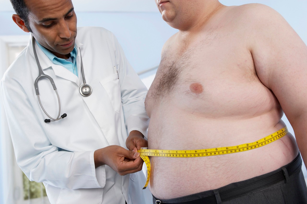 Medical consultation. General practioner measuring the waist of an obese patient. --- Image by © Adam Gault/Science Photo Library/Corbis