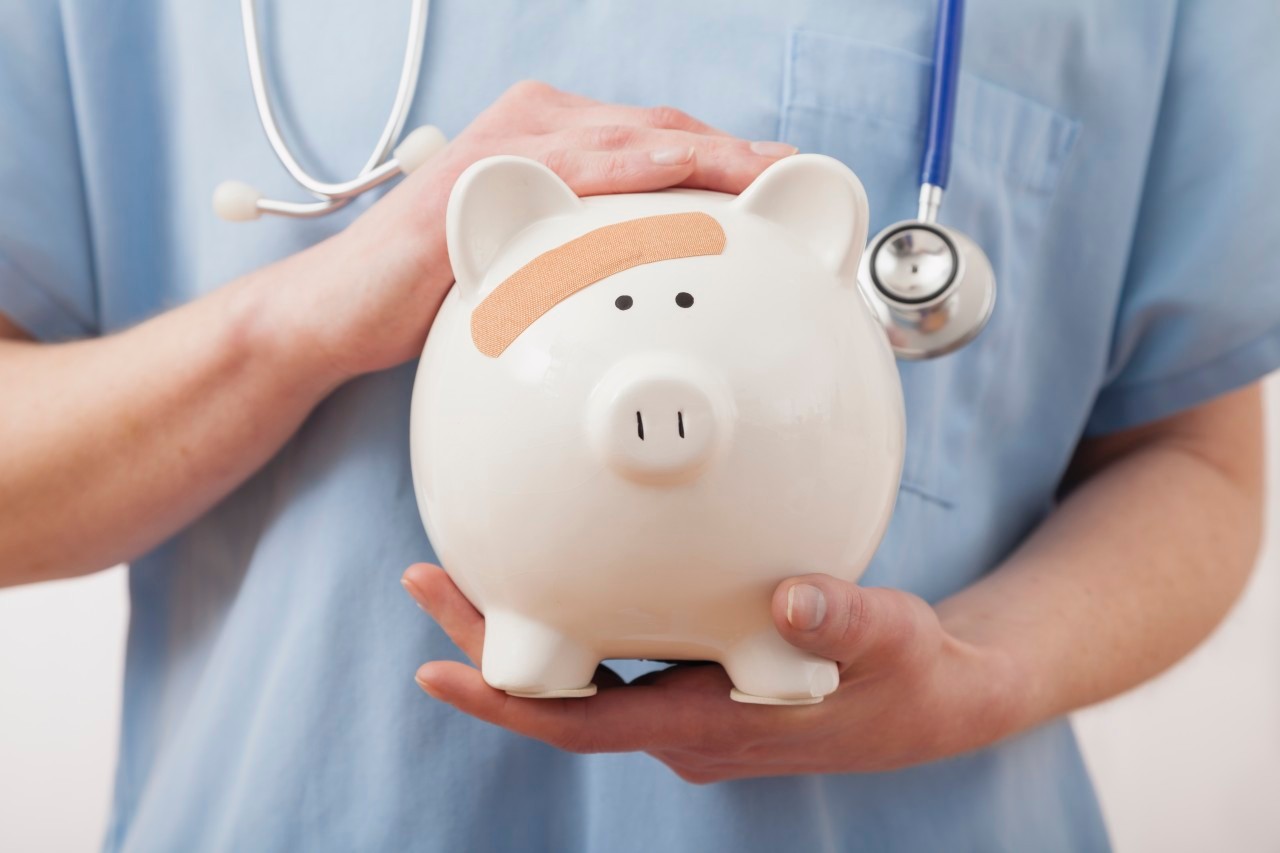 2011 --- Nurse holding piggy bank, midsection --- Image by © Greg Vote/Tetra Images/Corbis