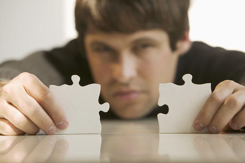 Man with puzzle pieces --- Image by Â© Tetra Images/Corbis