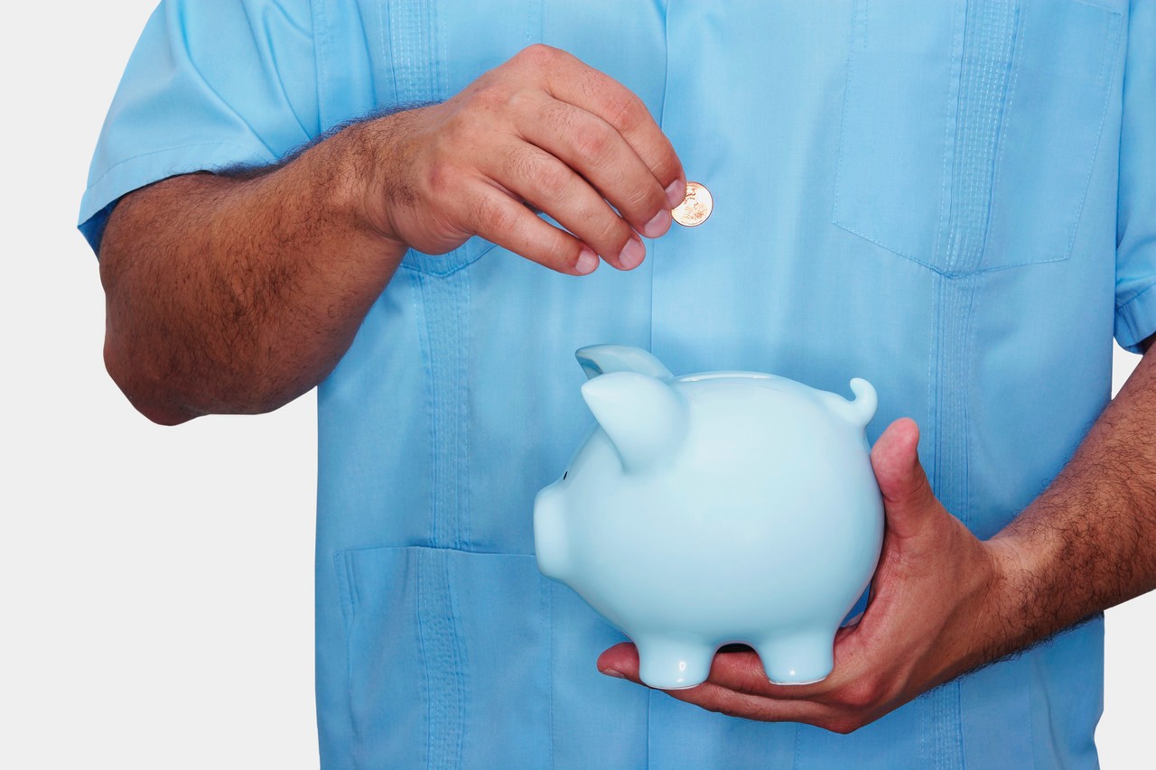 Man inserting a gold coin into a piggy bank --- Image by © Hola Images/Corbis