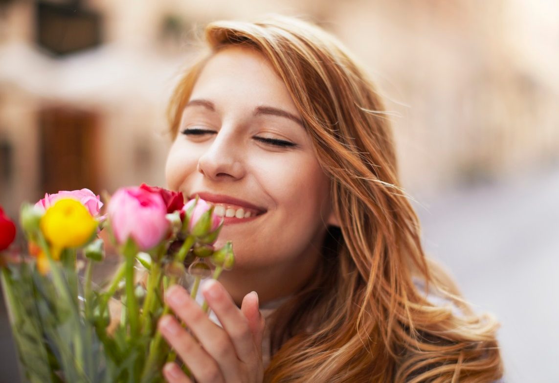 14 Mar 2014 --- Smiling young woman smelling a bunch of flowers --- Image by © Moof/Corbis