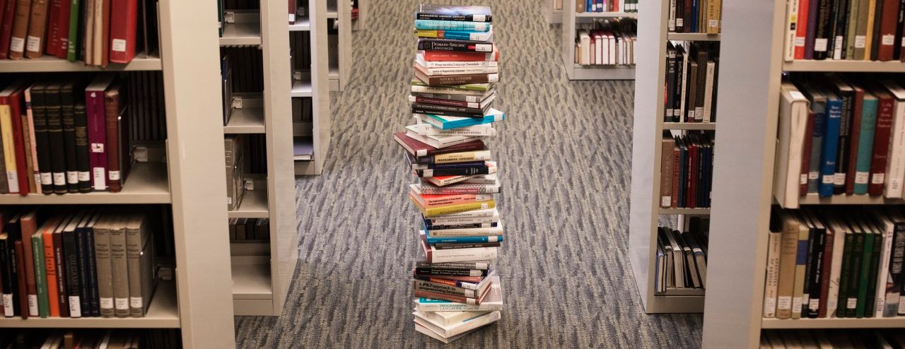 Pile of books standing in library lane --- Image by © Hiya Images/Corbis