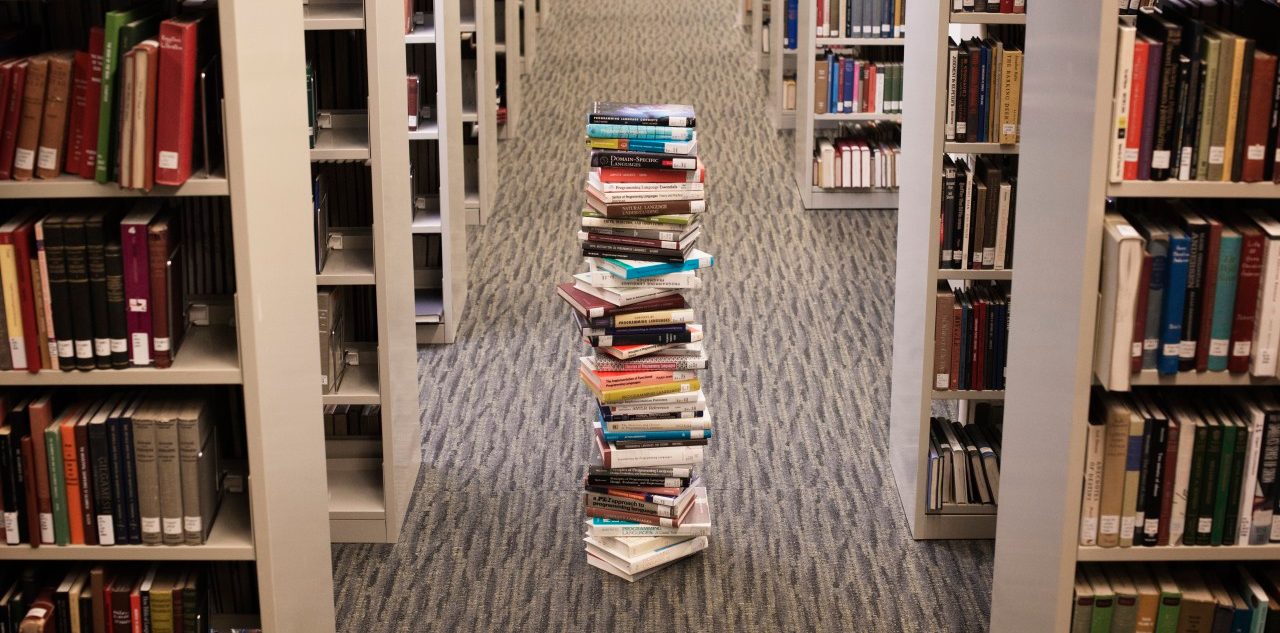 0042-11-30T00:00:00.000Z Pile of books standing in library lane --- Image by © Hiya Images/Corbis